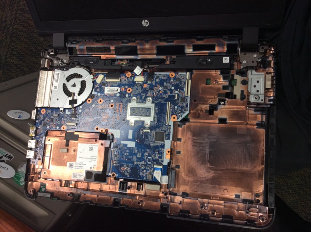 Soot and heat-damaged laptop motherboard undergoing electronics restoration